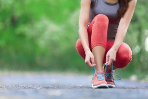 donna in tuta da ginnastica che si allaccia le scarpe