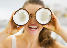 donna con 2 metà di cocco davanti agli occhi su sfondo della camera