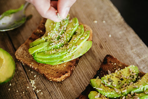 Mettere a mano i cereali nel pane integrale con fette di avocado