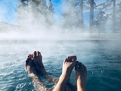 coppia alla spa con piedi nell'acqua e bosco attorno