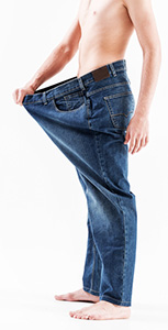 uomo che misura chili persi allargando la cinta dei pantaloni