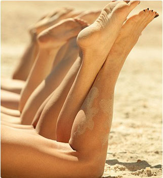 gambe e piedi di donne sulla spiaggia con sabbia addosso