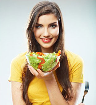 donna che sorride con un'insalata fresca in una mano