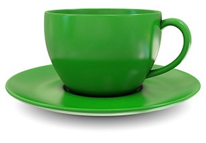 tazza verde che riposa su un piccolo piatto su uno sfondo bianco