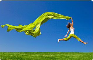 ragazza che salta su un prato verde con cielo azzuro