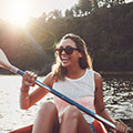 donna in occhiali da sole che sorride e che va kayak sul lago