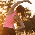 una donna in abiti allenamento che fa stretching al tramonto