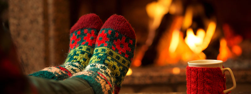 donna con calze di Natale accanto al fuoco con una tazza di tè