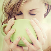 viso di donna che beve infuso detox da tazza verde