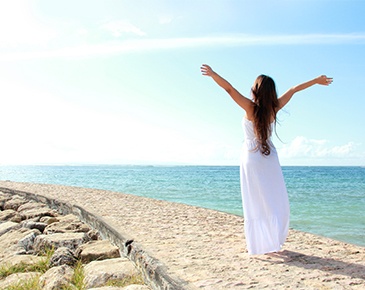 donna con abito lungo bianco al mare che si gode la linea e il sole