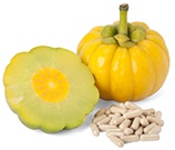 garcinia cambogia frutto arancione vicino a garcinia tagliata a metà con pillole a fianco