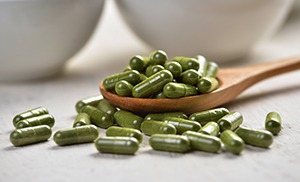 capsule verdi di moringa su cucchiaio di legno marrone