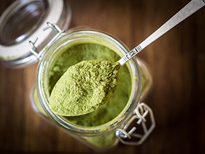 polvere di moringa verde in tazza di vetro su tavolo marrone