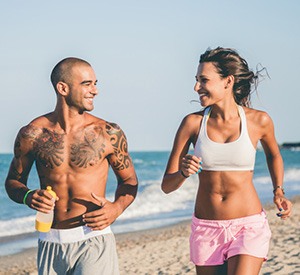 coppia che fa sport correndo sulla spiaggia per mantenersi in forma