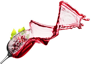 vino rosso versato da un calice di vetro con gracini di uva rossa