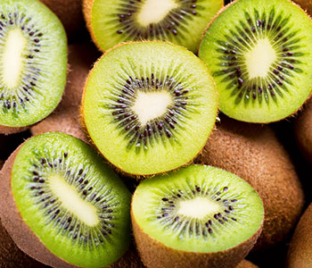 kiwi verdi tagliati a metà su kiwi interi marroni visti dall'alto