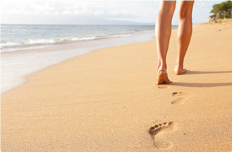 donna che cammina sulla spiaggia con segni di piedi sulla sabbia