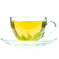 tazza trasparente con tè verde e piattino su sfondo bianco